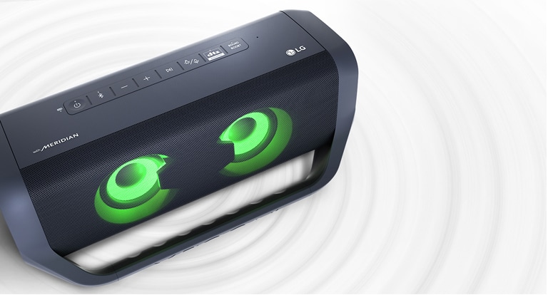 Top-down angled shot of an LG XBOOM Go on a white surface. It has green lighting and a ripple effect under the product.