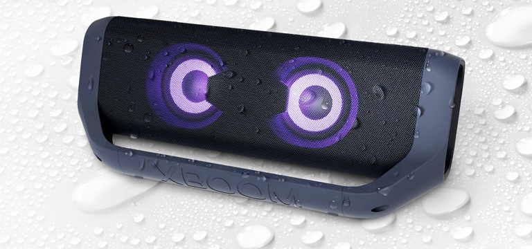 On a white background, LG XBOOM Go is facing up to the left. There are water droplets on and underneath the product.