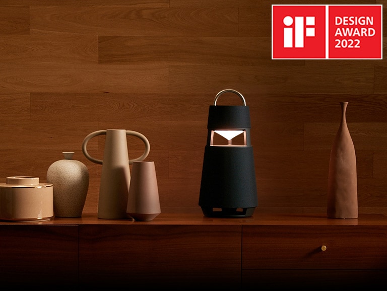 Image of the XBOOM 360 with sculptures on a shelf in a wood-toned interior background.