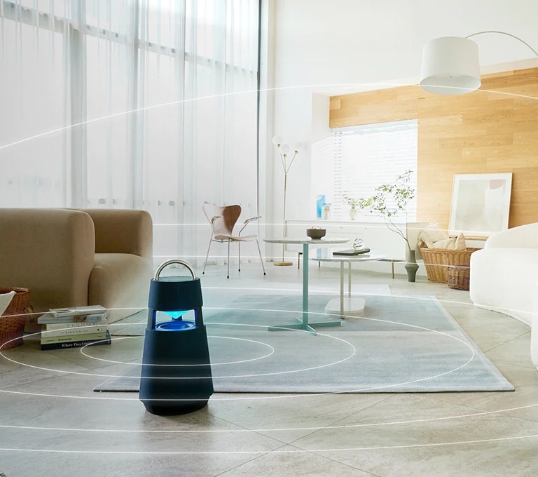 Image of sound waves spreading around XBOOM 360 lying on the floor of a minimal living room space.