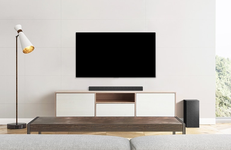A TV, soundbar, and subwoofer placed in a plain living room.