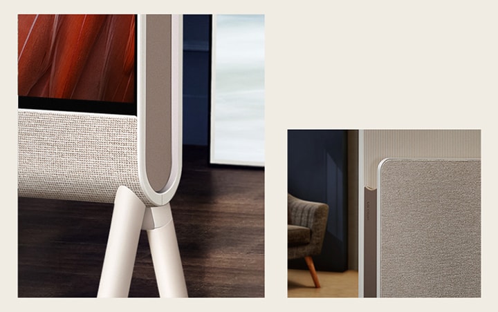 LG OLED Posé's bottom corner is seen closeup from the front focusing on the fabric, with wood flooring in the background.   The fabric of LG OLED Posé's Media Shelf and LG Objet logo are seen closeup with an armchair in the background.