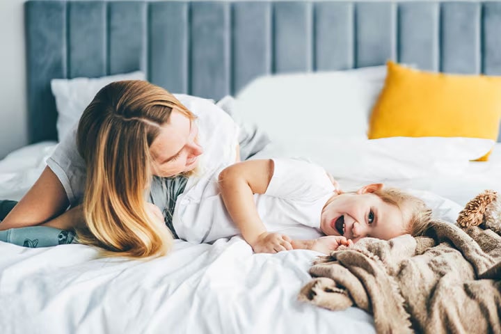 The child and mother are lying on the bed.