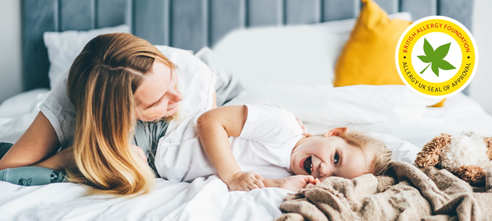 The child and mother are lying on the bed.