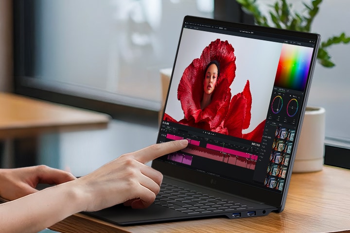 This image shows the LG gram Pro laptop being used for creative editing with touch input, displaying a colour grading interface and timeline on the screen.	