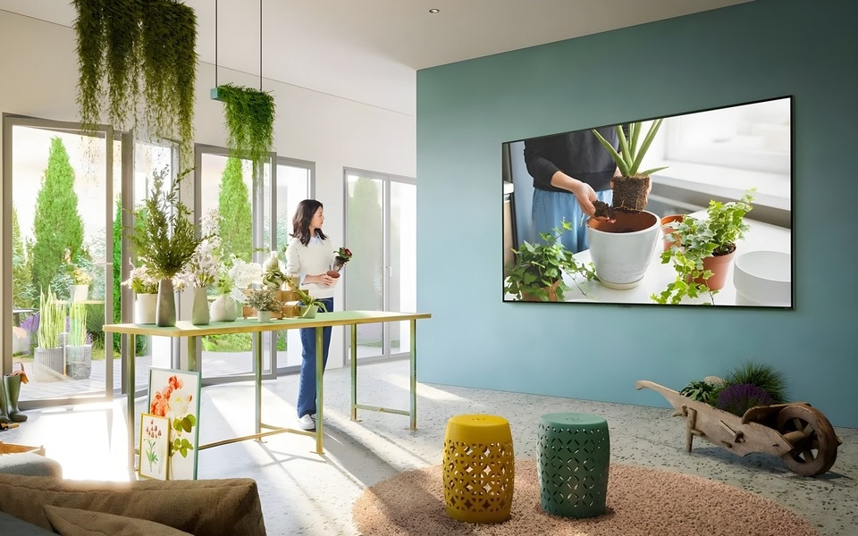 Mujer cuidando plantas, viendo el TV de LG