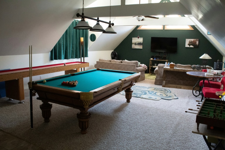 A man cave set up as a gaming room with high-quality screens, gaming equipment, comfy chairs, and cool lighting for a fun entertainment space.