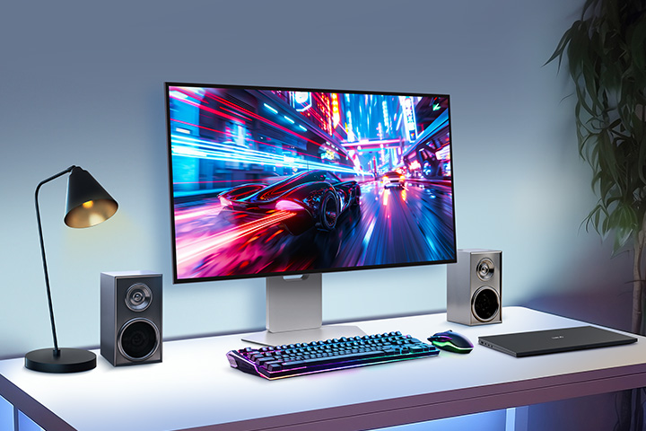 A 32-inch gaming oled monitor is positioned in the center of the desk, with various IT devices placed around it.
