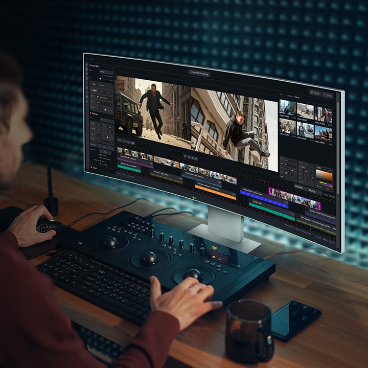 A guy is working with a video-creating program on UltraFine Monitor.	