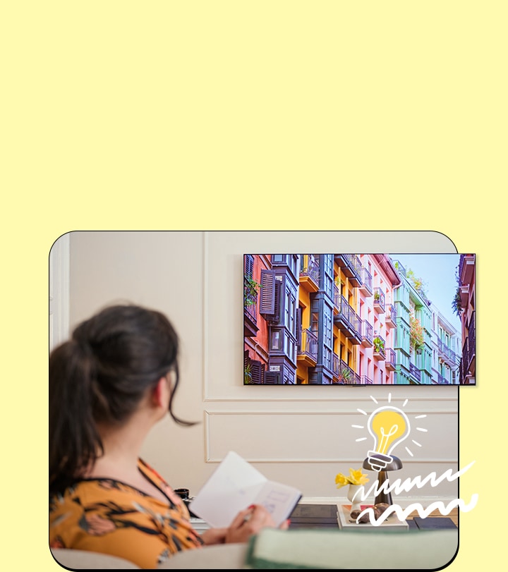 The woman is watching TV with a notebook.