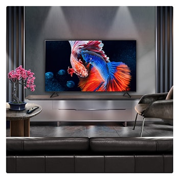 A family sits on a couch facing a LG QNED TV sitting above a TV stand with a little girl pointing to a screen depicting two dolphins. The title talks about how you can enjoy high resolution on a massive screen.