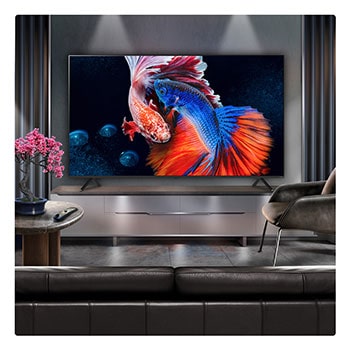 A family sits on a couch facing a LG QNED TV sitting above a TV stand with a little girl pointing to a screen depicting two dolphins. The title talks about how you can enjoy high resolution on a massive screen.