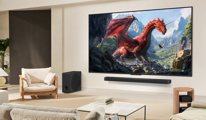 A family sits on a couch facing a LG QNED TV mounted on a wall above a LG Soundbar with a little girl pointing to a screen depicting two dolphins.