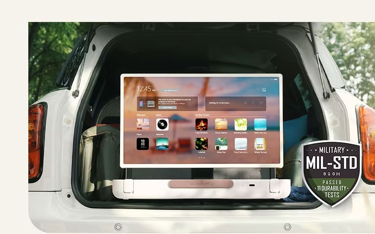 Front view of LG StanbyME Go. The product is placed in the car, the screen rorated horizontally, showing home screen. On the bottom-left side of the image, military spec icon is shown.