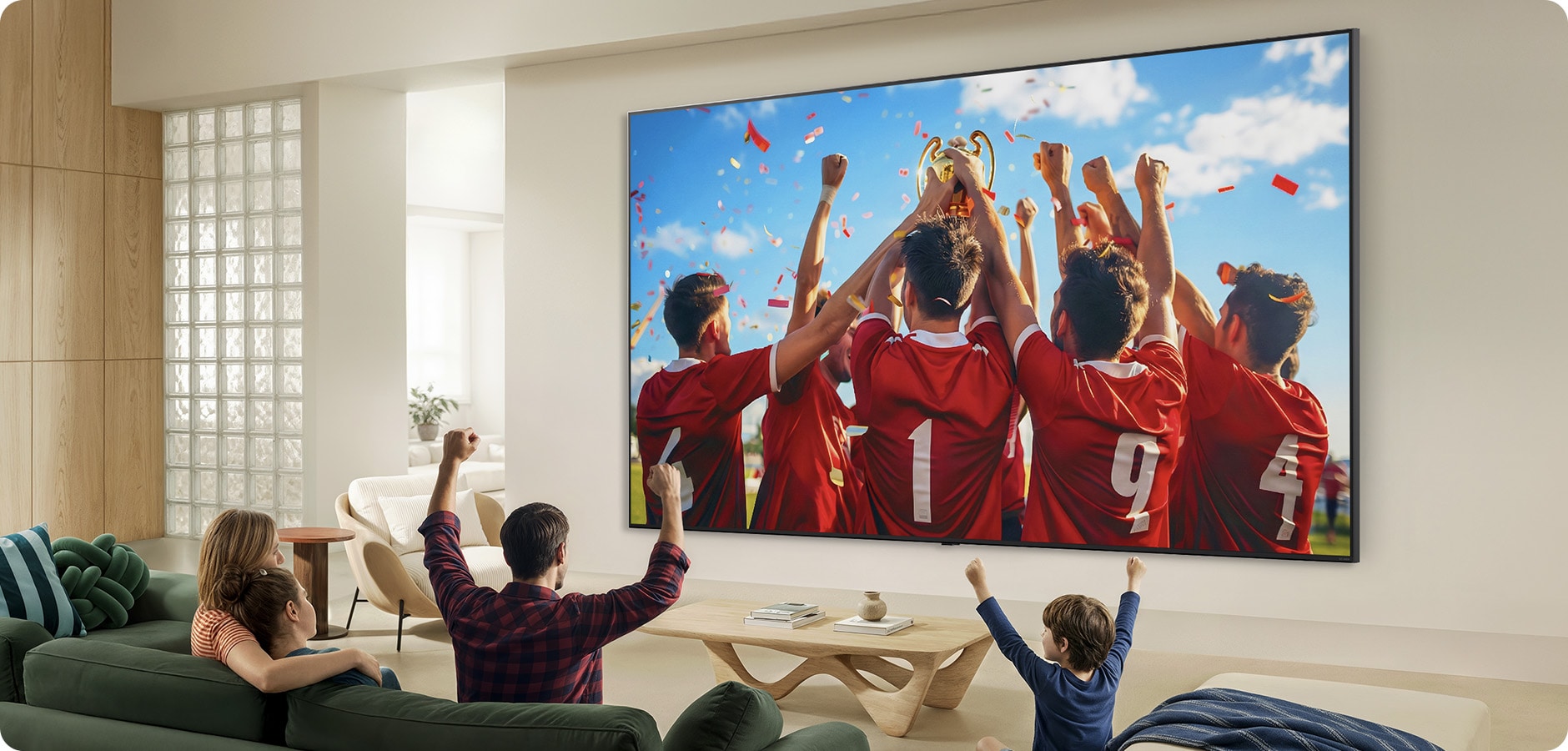 Living room scene with a family cheering while watching a soccer celebration on a very large wall-mounted TV