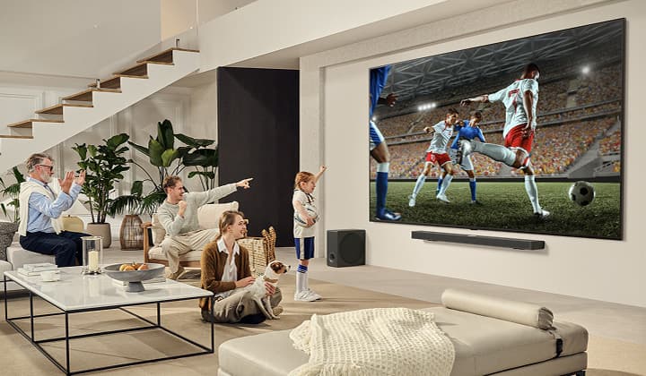 Một gia đình đang quây quần bên LG TV siêu lớn để xem một trận bóng đá đầy phấn khích trên màn hình lớn.