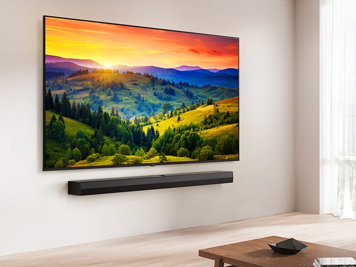 LG UHD TV được gắn trên tường cùng LG Soundbar trong không gian phòng khách hiện đại. Màn hình hiển thị hình nền màu sắc rực rỡ.