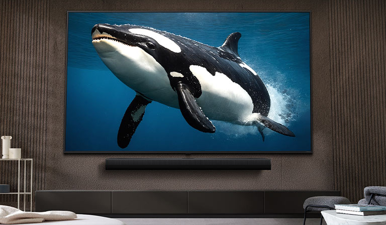 TV LG với màn hình cực lớn được gắn trên tường, phía dưới là loa LG Soundbar, trong một phòng khách hiện đại.
