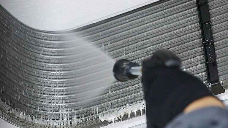 Một kỹ sư đang làm sạch bên trong máy điều hòa không khí âm trần.