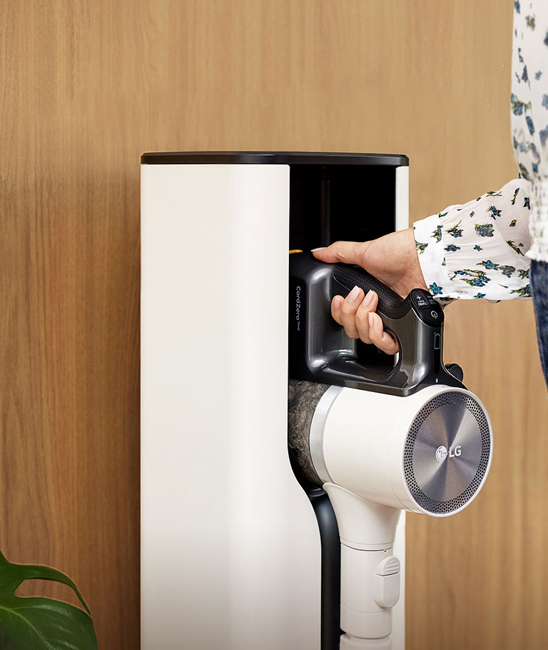 Một phụ nữ đang đặt máy hút bụi Cordzero™ vào tháp sạc.
