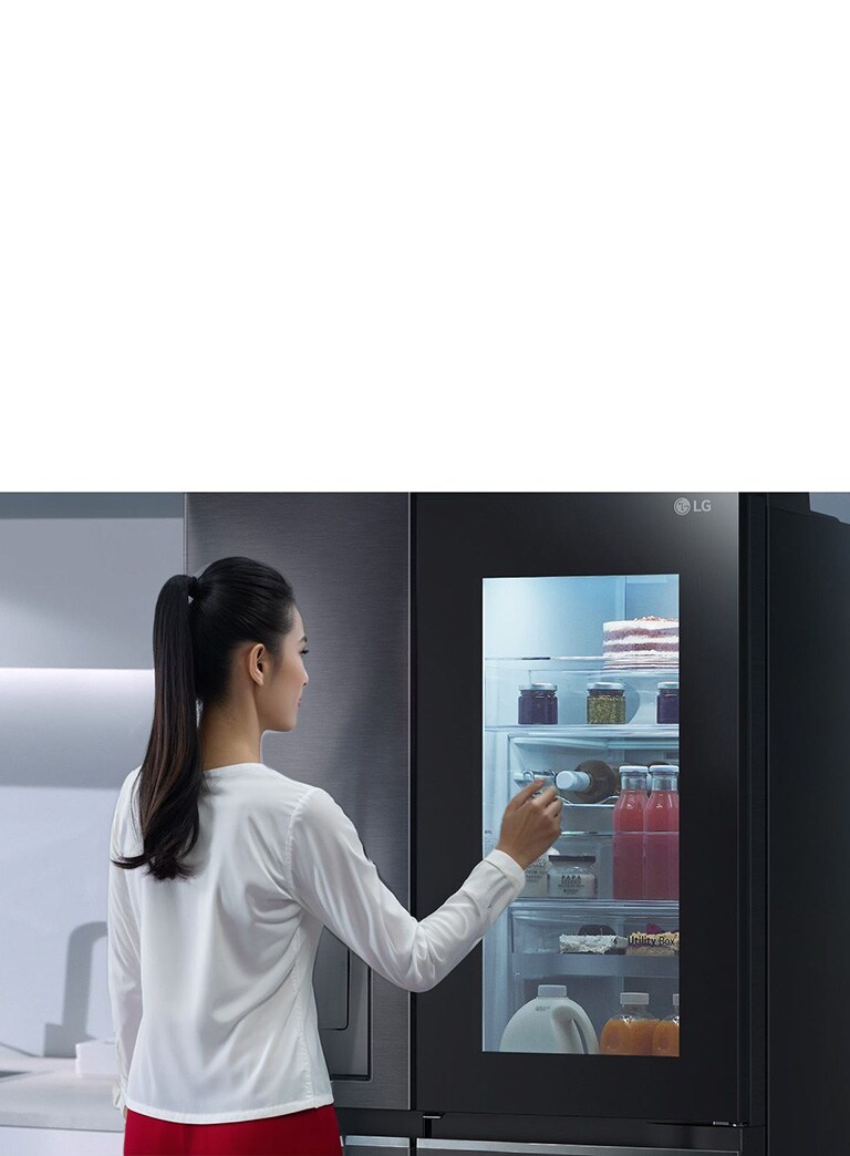 Video cho thấy một người phụ nữ đang đến gần tủ lạnh InstaView và gõ hai lần. Bên trong tủ lạnh sáng lên và cô có thể nhìn thấy thực phẩm trong tủ mà không cần mở cửa. Hình ảnh phóng to tập trung vào đồ uống ở cửa và sau đó thu nhỏ để thấy người phụ nữ từ phía sau khi cô mở cửa và lấy đồ uống.