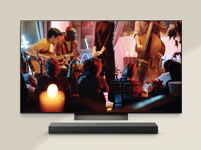 Một buổi hòa nhạc ấm cúng đang phát trên màn hình LG TV với LG Soundbar ở dưới.