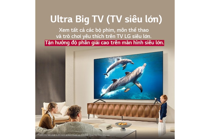 Cả gia đình ngồi trên chiếc ghế dài đối diện LG QNED TV nằm phía trên kệ TV, một cô bé chỉ vào màn hình đang chiếu cảnh hai chú cá heo. Tiêu đề nói về cách bạn trải nghiệm độ phân giải cao trên màn hình lớn.