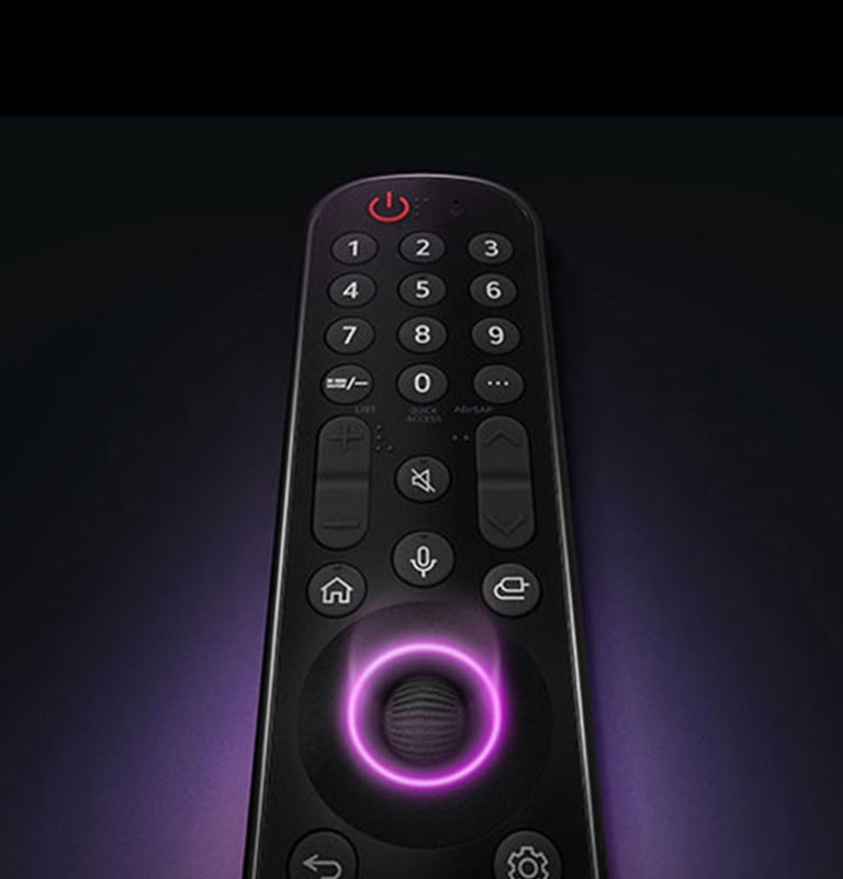 Điều khiển từ xa LG Magic có nút tròn ở giữa, khi ánh sáng màu tím neon phát ra xung quanh nút để làm nổi bật chúng. Ánh sáng tím dịu bao quanh điều khiển từ xa trên nền đen.