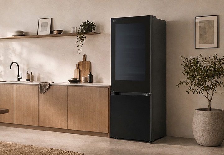 Tủ lạnh ngăn đá dưới LG màu đen với thiết kế cửa phẳng, đặt cạnh vách bếp gỗ và một chậu cây.