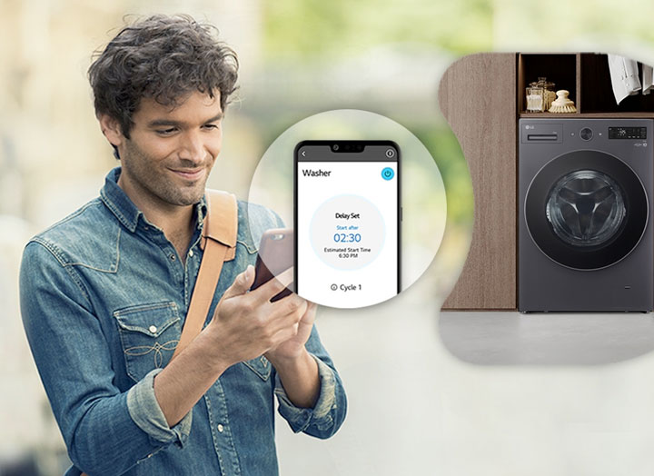 The man is looking at the smartphone and is showing the screen and washing machine image of the smartphone next to him