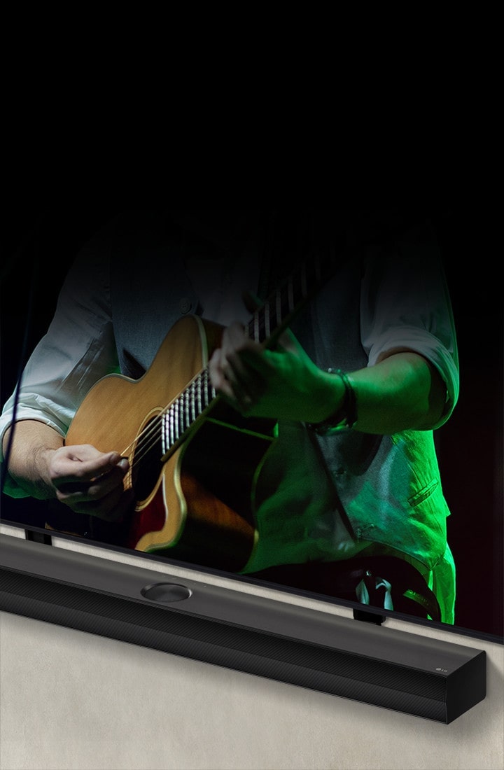 LG Soundbar against a black backdrop reveals its design starting from the left corner, then pans out to show the whole soundbar. An LG QNED TV appears. The Soundbar is against the wall with the lower screen of the TV being visible, displaying a man playing the guitar.
