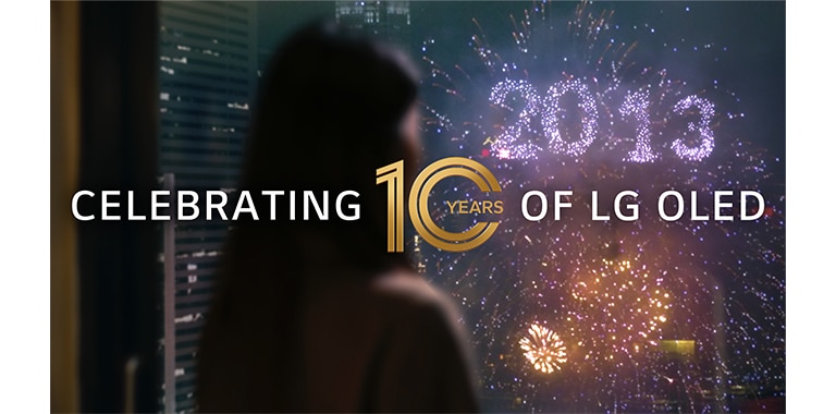 A woman watches a firework display from her window with a cluster that writes out 2013. The overlay text reads, "Celebrating 10 Years of LG OLED."