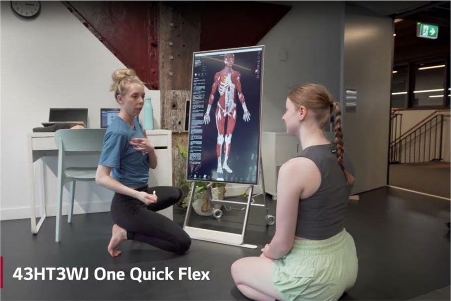 LG 43HT3WJ One Quick Flex used in a training studio as an instructor guides a student with an on-screen 3D anatomy model for body movement education