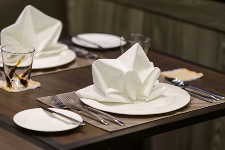 Restaurant table setting with neatly folded white napkins, highlighting professional hospitality