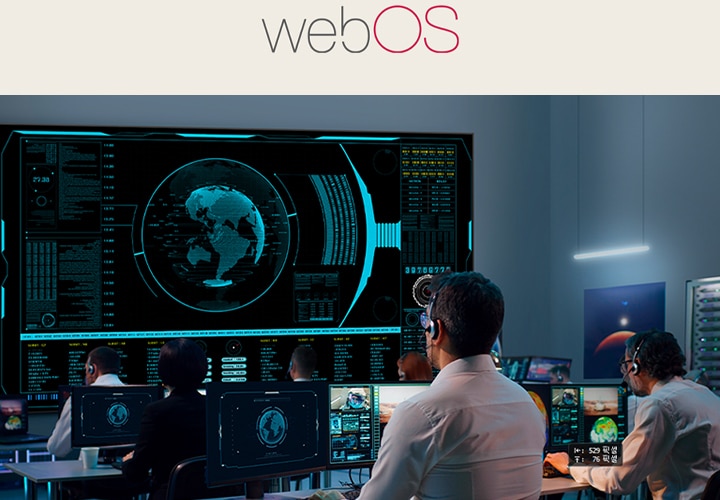 This image shows several people monitoring multiple displays in a control room.