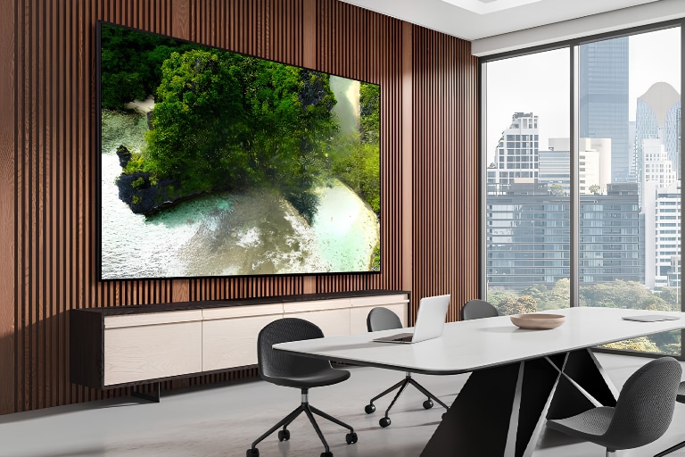 A signage display is mounted on the wall of a meeting room, clearly showing meeting content on the screen.