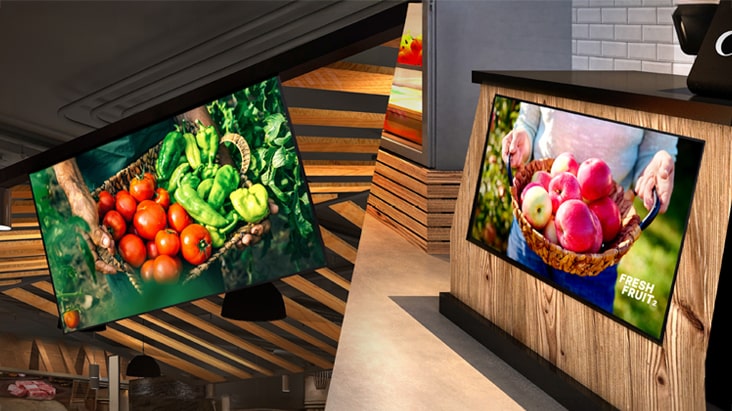 One UL5Q-M is installed on the store ceiling with a down tilt, and the other is mounted below the counter with an up tilt, both displaying content.