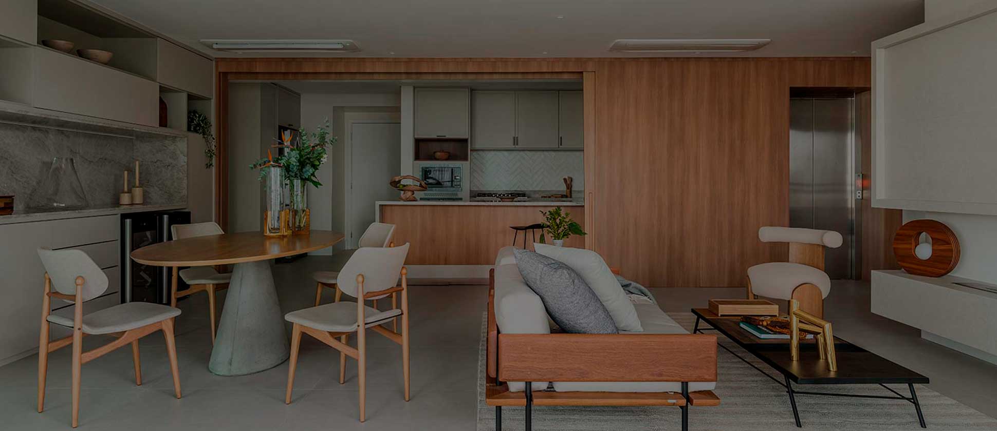 Sala de estar e jantar moderna e sofisticada, com móveis de madeira clara, mesa redonda e decoração minimalista, representando um lar acolhedor e elegante.