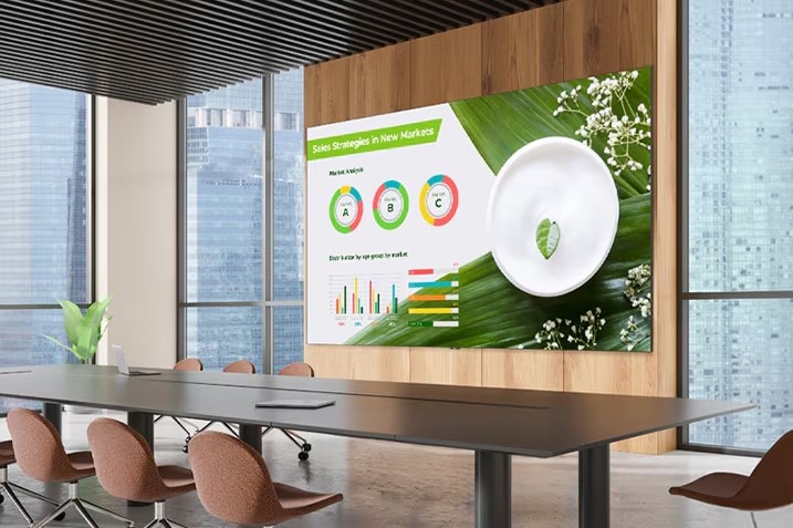 Um display amplo está instalado na parede do salão de conferências, e a apresentação é exibida de forma destacada e clara na tela grande.