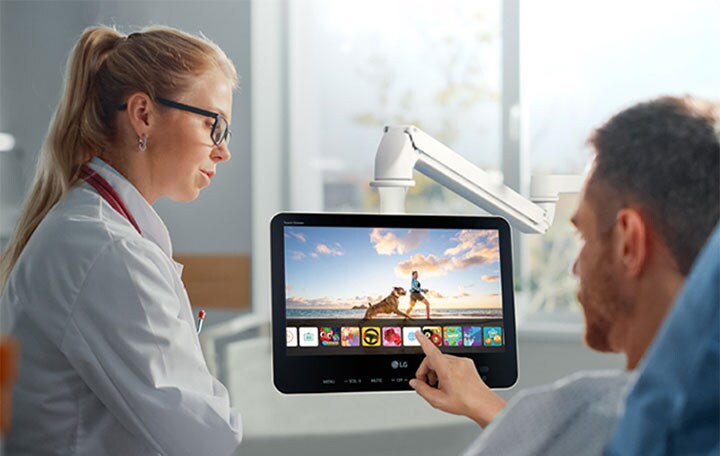 The patient is easily controlling his personal TV using touch, lying in the bed.