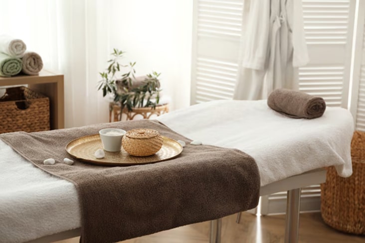 Sala de spa con cama de masajes, toalla y juego de té sobre una bandeja