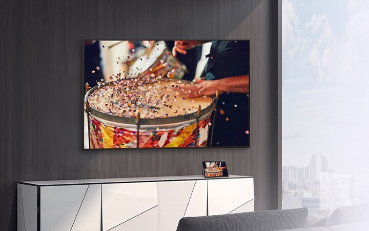 En la habitación hay un televisor montado en la pared y una tableta sobre el estante. El contenido en la tableta se reproduce y se muestra en el televisor.