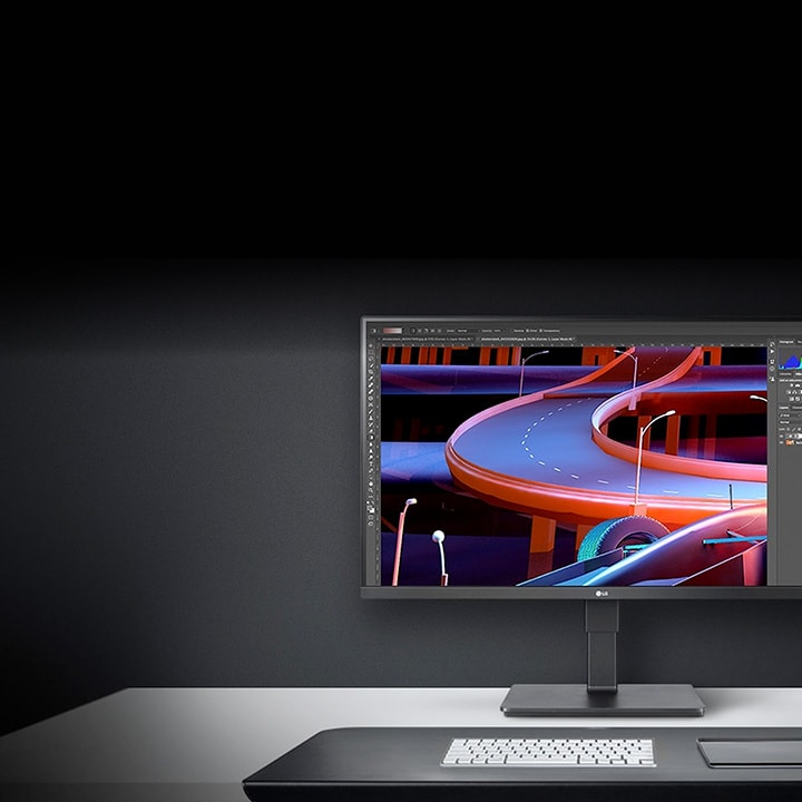 Monitor LG en un escritorio minimalista que muestra arte digital de coloridas carreteras curvas en un programa de diseño gráfico.