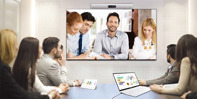 Se está realizando una videoconferencia, mientras las personas se proyectan en los carteles instalados en la pared.