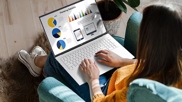 Eine Person sitzt bequem auf einem Stuhl und verwendet einen Laptop, auf dem eine Präsentation mit Diagrammen und Grafiken angezeigt wird. Eine Animation veranschaulicht den blendfreien Bildschirm, indem sie zeigt, dass selbst bei direkter Sonneneinstrahlung keine Lichtreflexion auftritt.