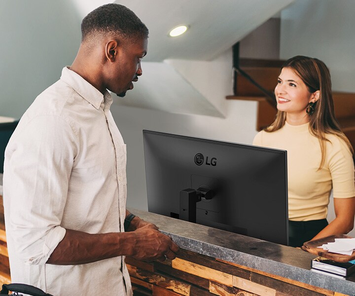 Eine Rezeptionistin spricht mit einem Mann am Empfang.