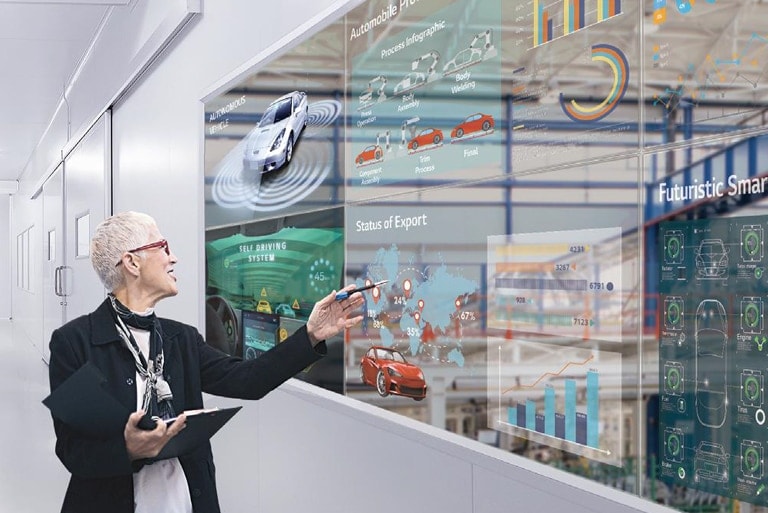 Eine Frau überprüft ihre Arbeit, indem sie sie auf dem transparenten OLED-Bildschirmen betrachtet, die an den Bürofenstern installiert sind.