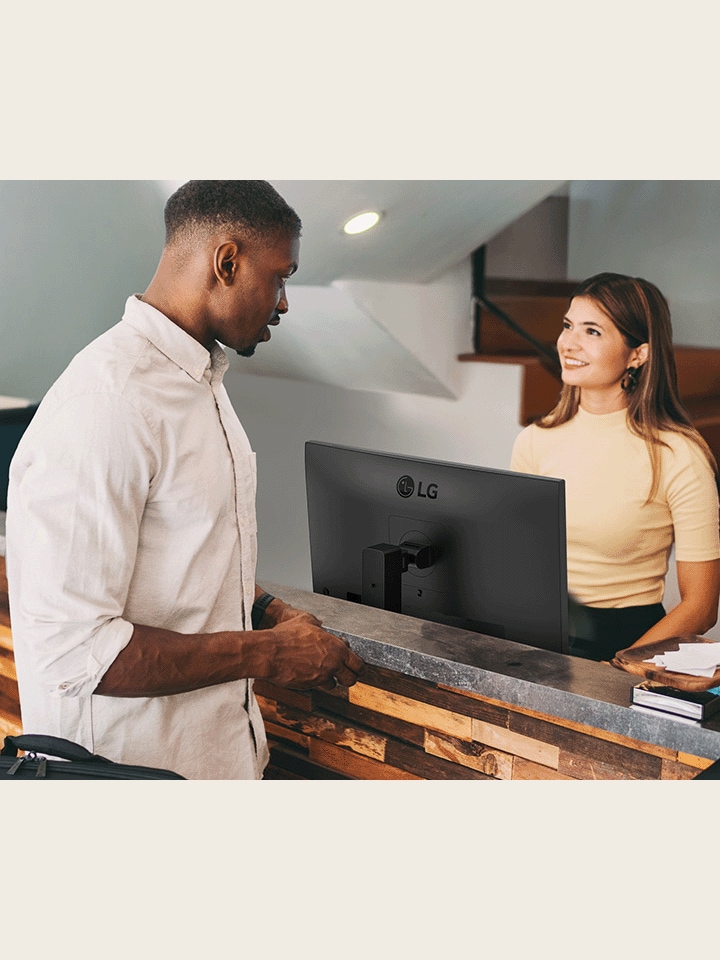 A female receptionist is talking to a man at the front desk.	