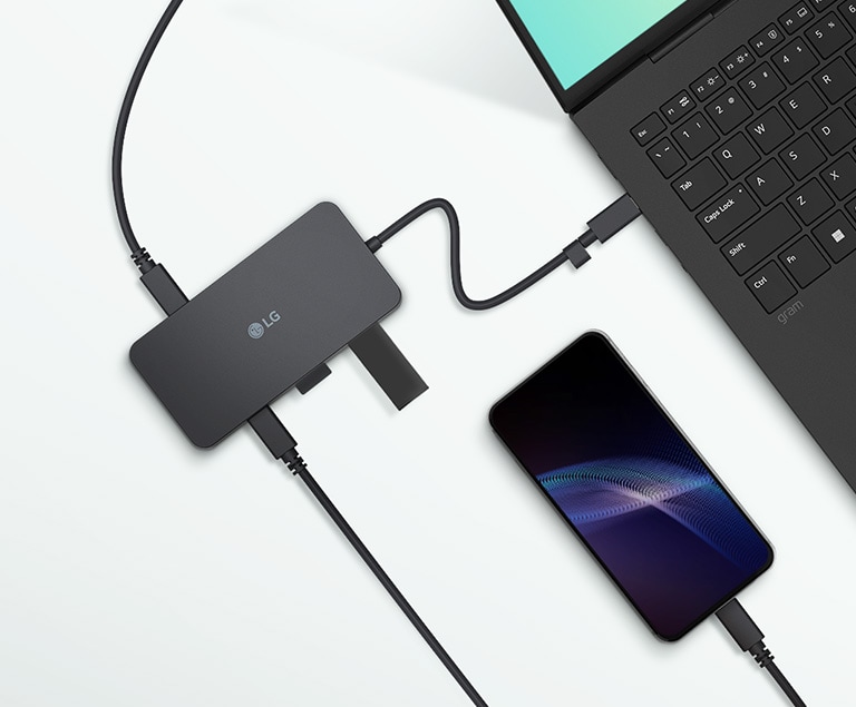 Laptop, Smartphone und LG-Dockingstation verbinden sich über Kabel auf einem weißen Tisch.