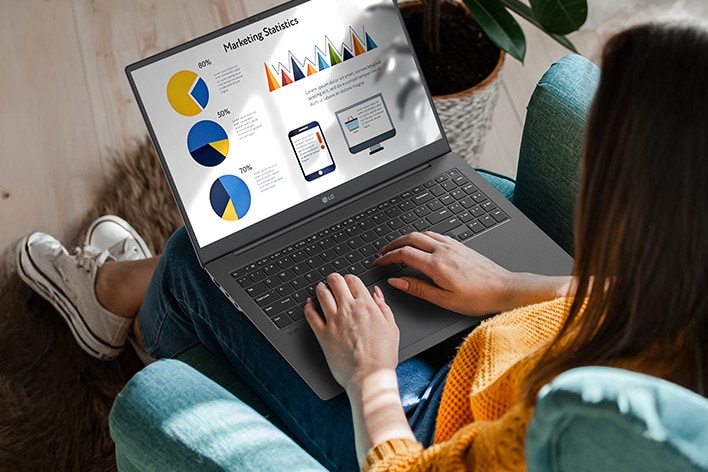 Eine Person sitzt bequem auf einem Stuhl und verwendet einen Laptop, auf dem eine Präsentation mit Diagrammen und Grafiken angezeigt wird. Eine Animation veranschaulicht den blendfreien Bildschirm, indem sie zeigt, dass selbst bei direkter Sonneneinstrahlung keine Lichtreflexion auftritt.
